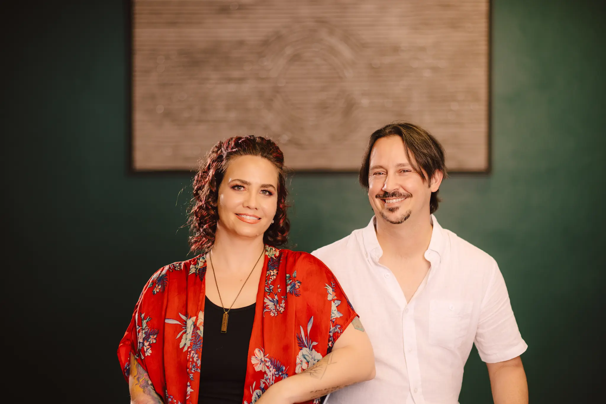 Carly in a red and black shirt next to Dominic in a white shirt, smiling